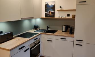A modern kitchen with bright cabinets and wooden surfaces. It is well equipped with a stove, oven, and kitchen appliances.