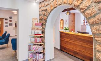 An inviting reception area with a historic stone arch. On the right, there is the wooden reception desk and a decorative pillow shelf.