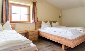 A cozy bedroom with two beds and a window. The furniture is made of light wood and offers a relaxed atmosphere.