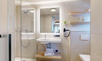 A modern bathroom with a shower and an elegant sink. Bright walls and shelves create an inviting atmosphere.