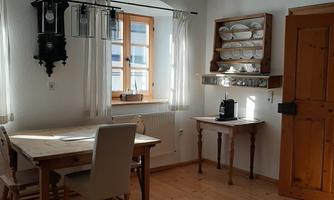 A cozy dining area with a table and chairs. The room has wooden floors and a warm atmosphere.