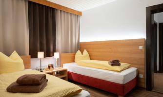 A cozy room with two twin beds and warm colors. The windows are decorated with elegant curtains and there is soft lighting.