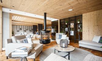 A modern living room with a wooden ceiling and cozy furniture. In the center stands an elegant fireplace that creates an inviting atmosphere.