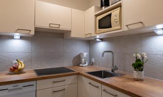 A modern kitchen with light cabinets and a wooden countertop. On the table are fruits and an orchid.