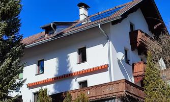 A beautiful house with a wooden balcony and sun protection. The clear blue sky makes the scene particularly inviting.