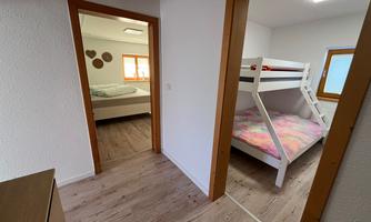 A bright and cozy apartment with two bedrooms. In the foreground, there is a room with a bunk bed.