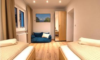 A cozy room with two beds and a blue bean bag. On the wall hangs a picture of a mountain landscape.