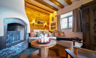A cozy living room with a wood stove and an inviting seating area. The walls are made of wood and the decoration gives a warm atmosphere.
