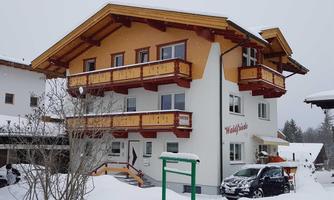 A snow-white building with colorful balconies in a winter landscape. The entrance is inviting and the surroundings are covered in snow.