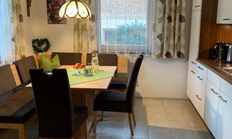 An inviting dining area with a wooden table and comfortable chairs. The modern curtains and warm light create a cozy atmosphere.