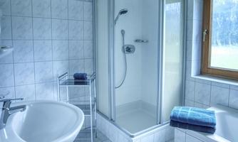 A modern bathroom with a shower and a bathtub. Towels are neatly folded and a window provides natural light.