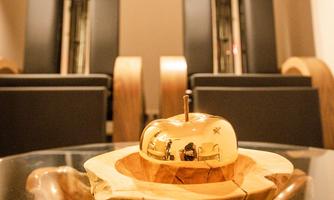 A stylish interior with two modern chairs in the background. In the foreground, a golden bell rests on a wooden board.