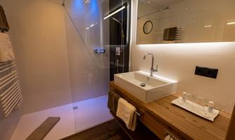 A modern bathroom with an elegant shower and a stylish sink. The wooden surface and soft lighting create a cozy atmosphere.