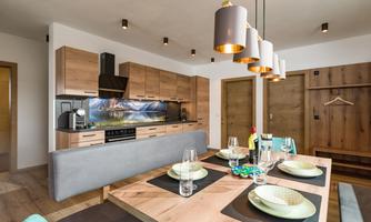 A modern kitchen with wooden furniture and a spacious dining table arrangement. The room is bright and welcoming, perfect for social evenings.
