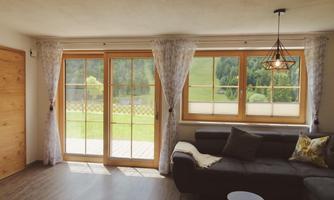 A bright living area with a comfortable sofa and large windows. View of a green landscape outside with plenty of natural light.
