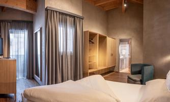 A modern hotel room with wooden details and large windows. The decor is simple and cozy, ideal for relaxing stays.
