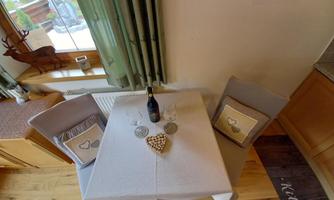 An elegant table with two chairs and a bottle of wine. The atmosphere is cozy and inviting.