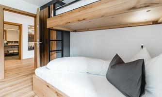 A cozy bedroom with a bunk bed and a light wood design. The room has a modern look and is well-lit.
