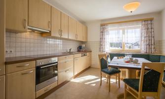 A bright and cozy kitchen with light wooden cabinets and a large window. The table is set and invites you to eat.