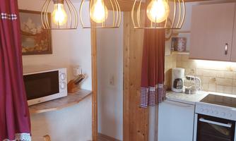 A cozy little kitchen design with warm light sources. The kitchen is well-equipped and has an inviting atmosphere.
