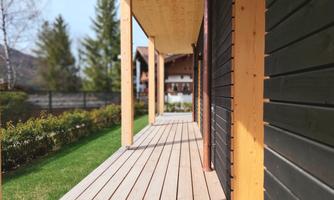 A modern wooden walkway with a clear view of the garden and the surrounding trees. The architecture is simple and harmonious with nature.