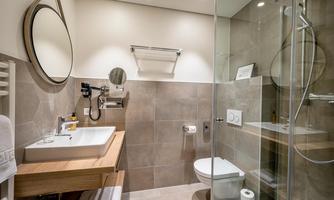 A modern bathroom with a glass shower and a stylish sink. The walls are in neutral tones and there is plenty of light.