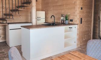 A modern kitchen in a wooden house with a bright, open atmosphere. The wood and steel table complements the elegant furnishings.
