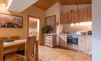 A cozy dining room with a wooden table and chairs. The modern kitchen is well-equipped and offers an inviting atmosphere.