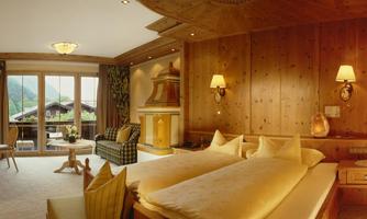 A cozy room with two beds and warm wood elements. Large windows offer a view of the landscape.