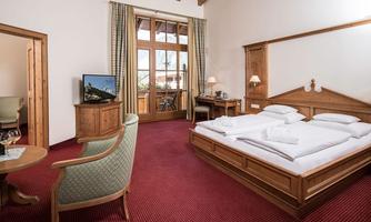 A cozy hotel room with a large bed and a small seating area. Large windows let in plenty of light and offer a beautiful view.