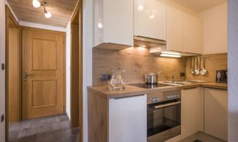 A modern kitchen with wooden and white cabinets. It is well-equipped with a stove, cooking utensils, and a cozy atmosphere.