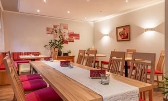 A modern restaurant with wooden and red furniture. The atmosphere is welcoming and well-lit.