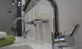 A modern sink with a shiny faucet and a towel. The surroundings appear clean and elegant.