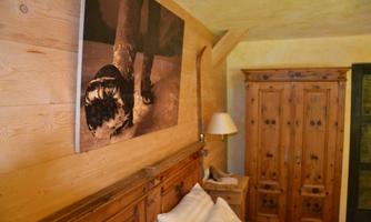 A cozy bedroom with wooden walls and a large wardrobe. An artistic picture hangs on the wall.
