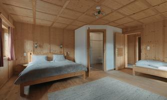A modern bedroom with wooden paneling and two beds. The room is bright and simply furnished, ideal for a peaceful stay.