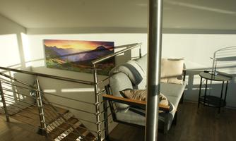 A bright, inviting room with a comfortable sofa and a small table. A picture of a mountain landscape hangs on the wall.