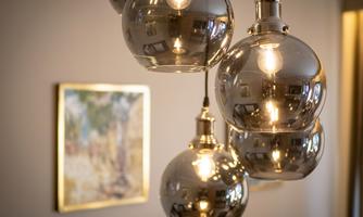 A modern pendant lamp with several glass spheres hangs from the ceiling. In the background, a painted artwork is visible on the wall.