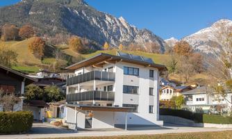 A modern building in a picturesque landscape. In the background, impressive mountains and colorful trees can be seen.