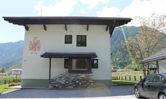 A modern building in a rural setting with a mountainous backdrop. The facade is bright and has decorative elements.