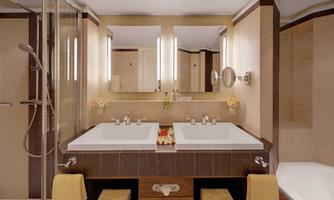 A modern bathroom with two sinks and clear mirrors. The walls are painted in warm tones and there is a spacious shower.