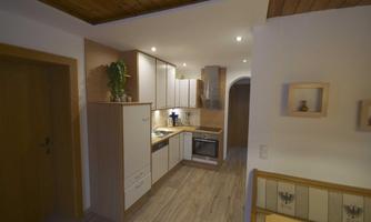 A modern kitchen with bright cabinets and an oven. The room has an elegant wooden ceiling and a friendly overall impression.