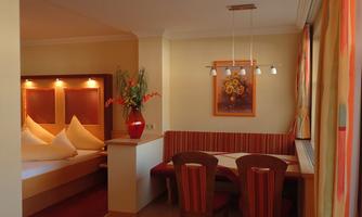 A cozy room with a double bed and a dining table. The warm colors and decorative elements create an inviting atmosphere.