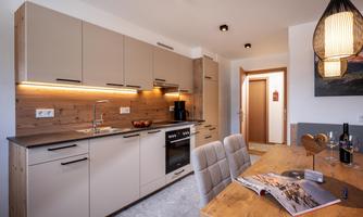 A modern kitchen with wood and gray tones. The dining area is cozy and invites you to linger.