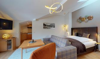 A cozy room with a double bed and a stylish seating area. The modern decor and warm colors create an inviting atmosphere.