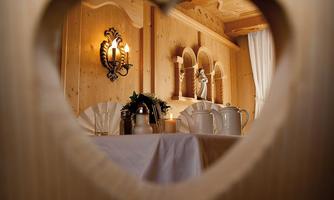 A view through a heart-shaped window onto a cozy table with a teapot and decoration. The warm wood tones give the room an inviting atmosphere.
