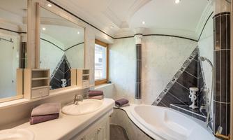 A modern bathroom with a bathtub, sink, and large mirrors. Bright colors and appealing tiles create an elegant atmosphere.