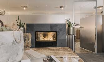 A modern room with an elegant fireplace and stylish plants. The table is decorated with a magazine and a glass.