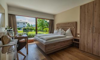 A bright bedroom with a large window overlooking the garden. The furniture is made of light wood and creates a cozy atmosphere.