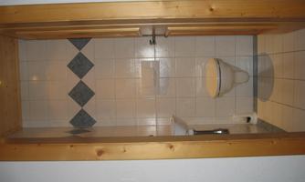 A small bathroom with a white toilet and bright tiles. The door is made of wood and is open to showcase the space.