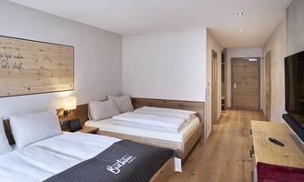 A modern room with two beds and wooden interiors. There is a television and warm light for a cozy atmosphere.